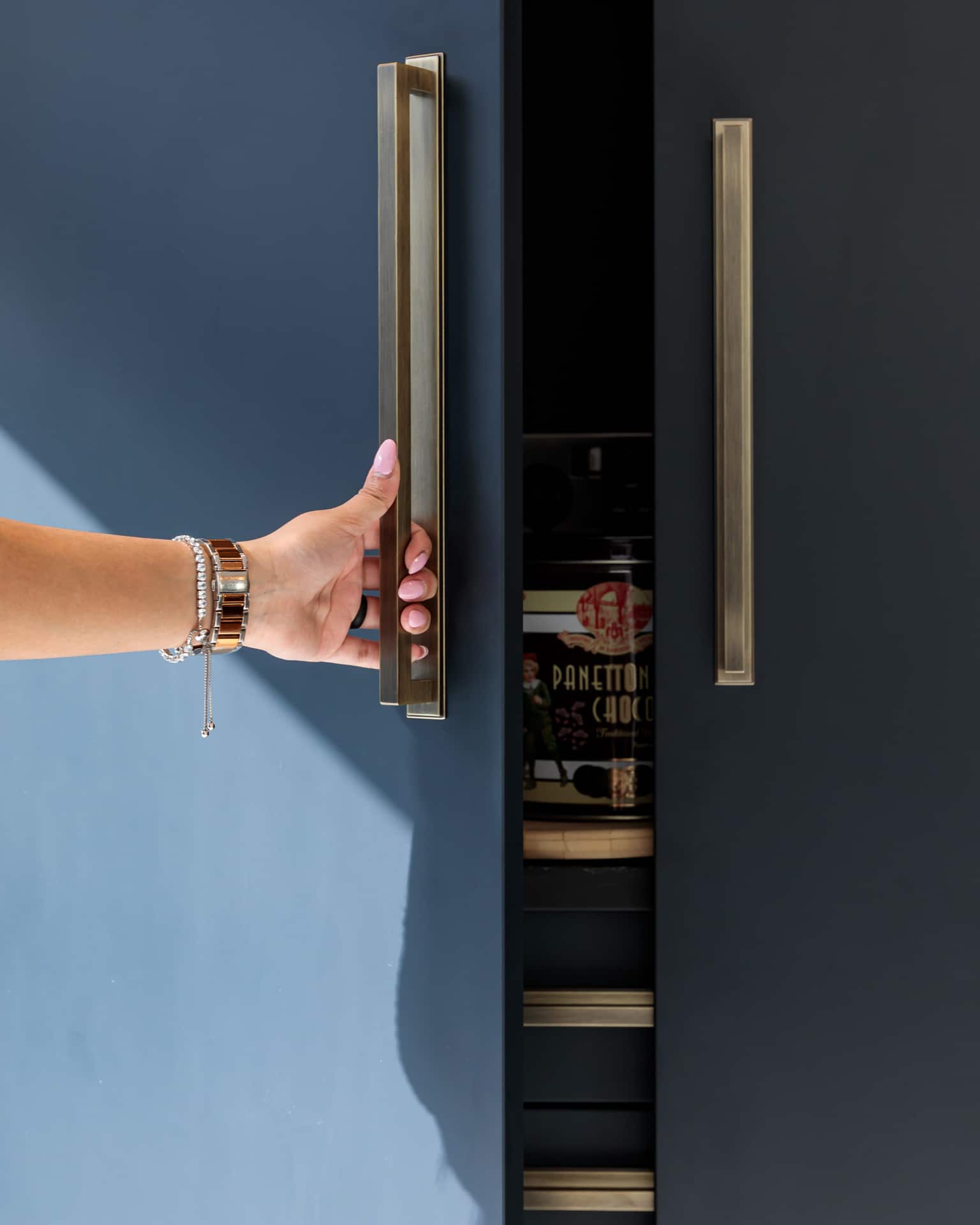 Arch KBB team member opening a modern cabinet with stylish handles, revealing neatly organised storage items inside.