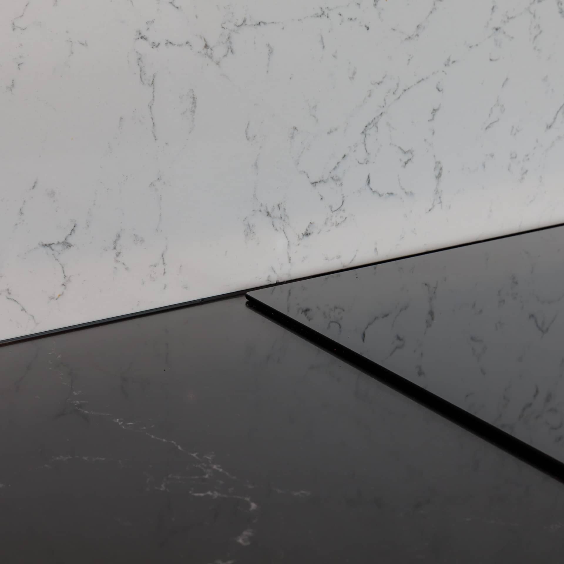 Close-up view of a sleek kitchen countertop featuring a black surface and a marble-patterned backsplash, showcasing the modern design elements used by an Arch KBB team member in interior design.