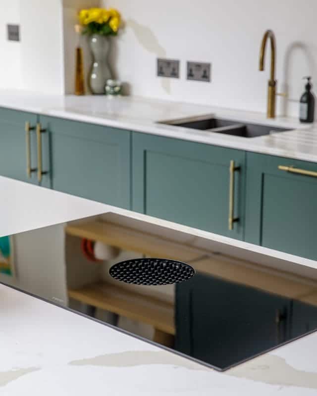 Modern kitchen design featuring a sleek black induction hob with a circular vent, paired with elegant green cabinetry and a minimalist countertop. An Arch KBB team member is present, showcasing the stylish and functional elements of contemporary kitchen interiors.