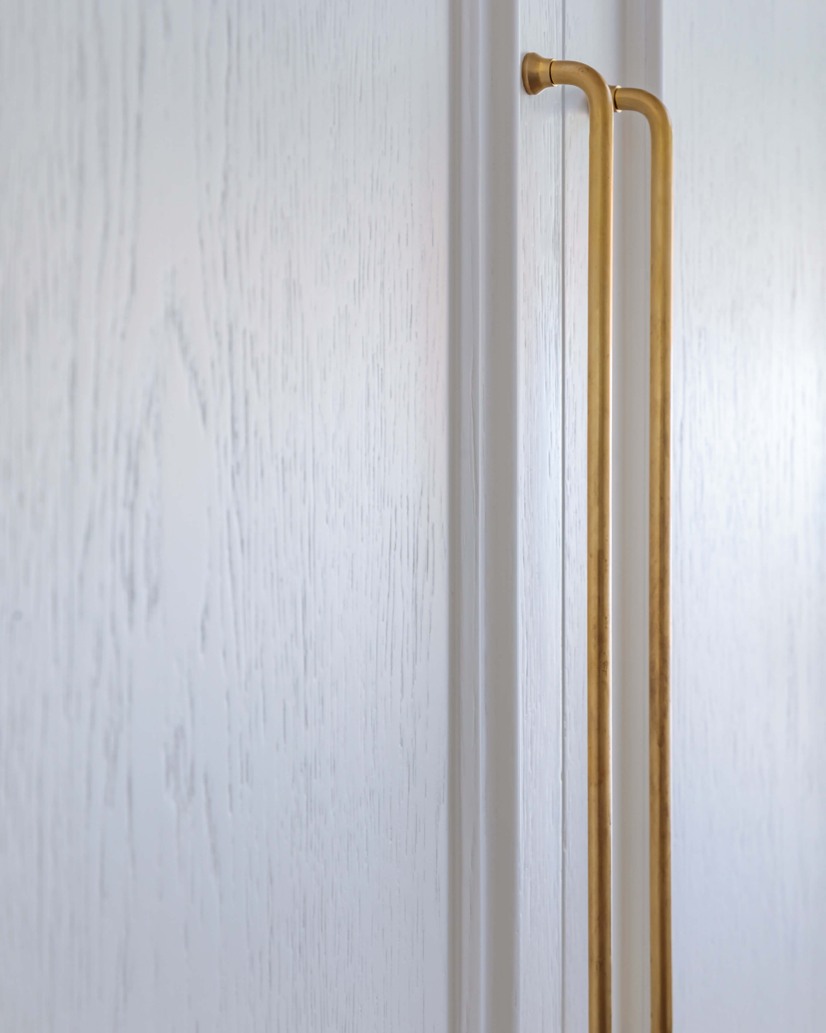 Close-up of a textured white door with a sleek gold handle, showcasing modern design elements. An Arch KBB team member is present, adding a professional touch to the scene.