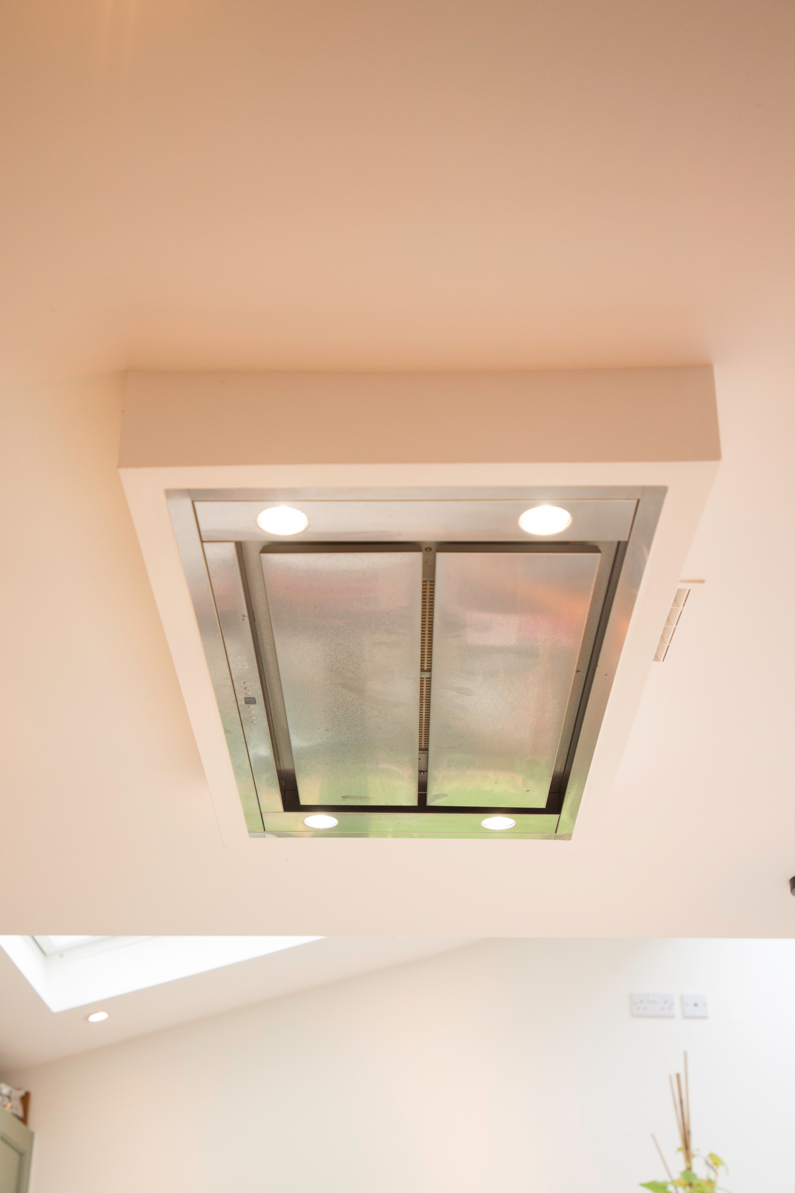 Ceiling-mounted kitchen extractor hood with integrated lighting, designed for effective ventilation and modern aesthetics, installed in a contemporary kitchen setting. An Arch KBB team member is present, showcasing expertise in kitchen design and installation.