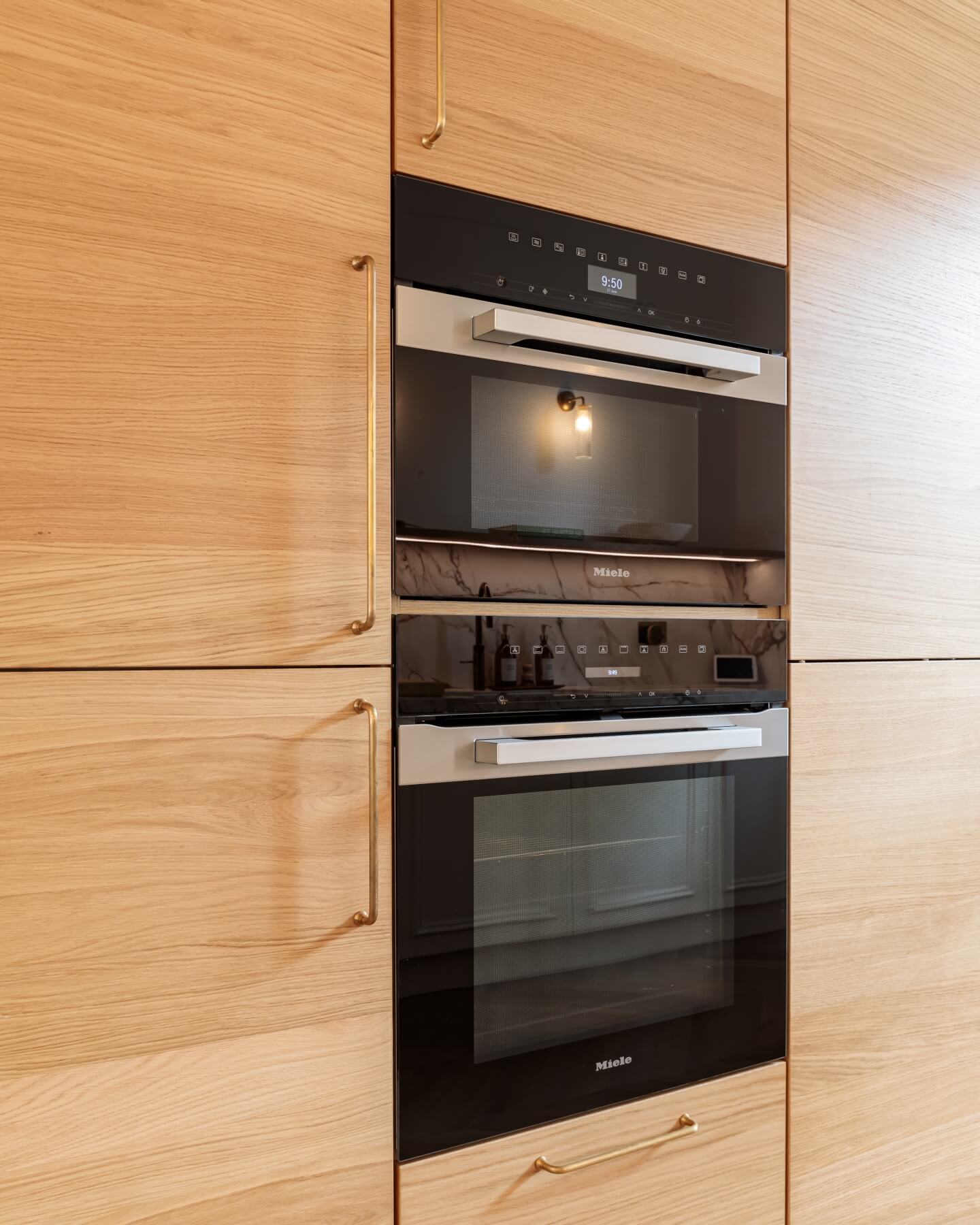 Modern built-in Miele double oven integrated into wooden cabinetry, showcasing sleek design and contemporary kitchen aesthetics.