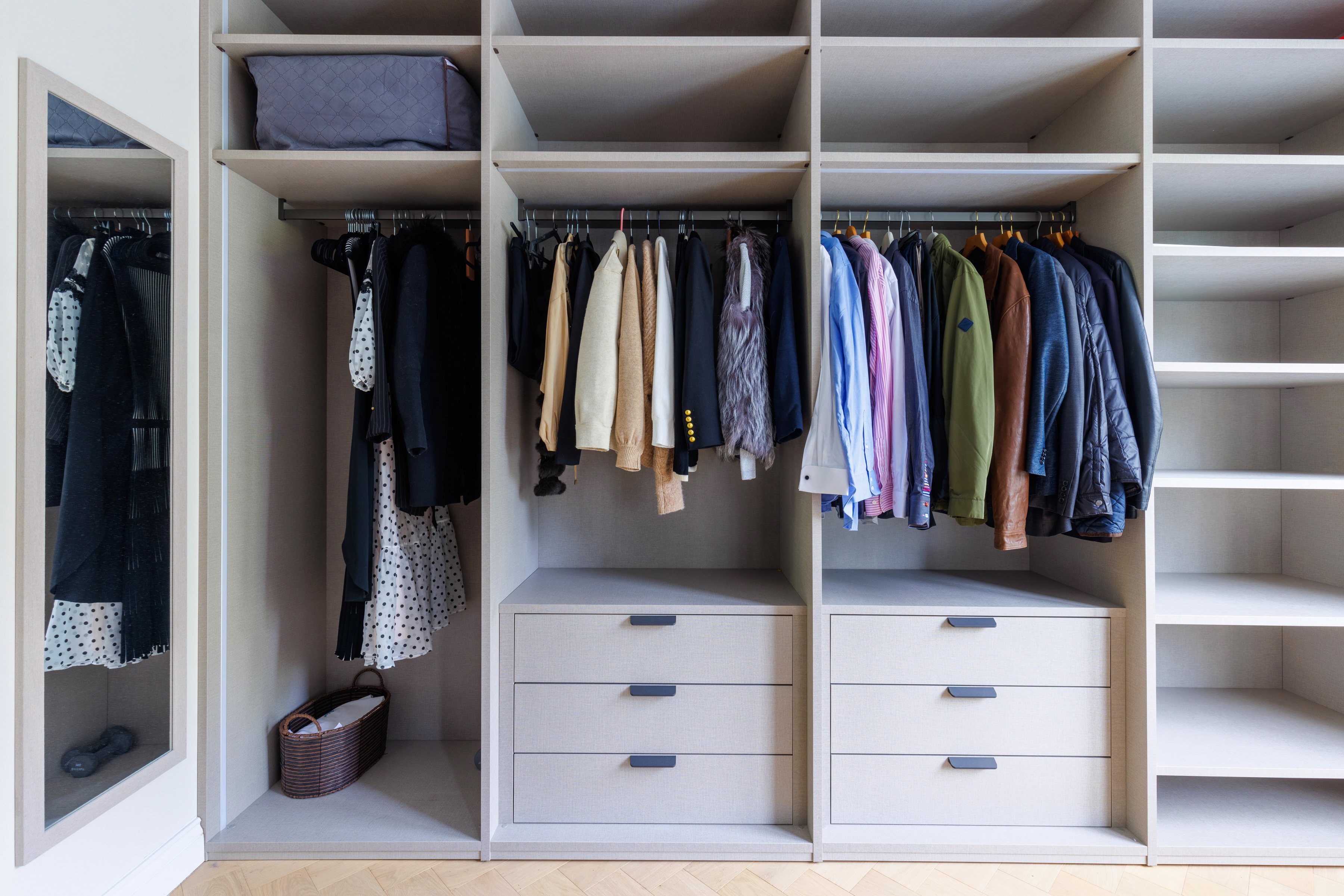 Organised wardrobe featuring a variety of clothing items neatly hung and stored, complemented by drawers for additional storage, showcasing a stylish and functional design by an Arch KBB team member.