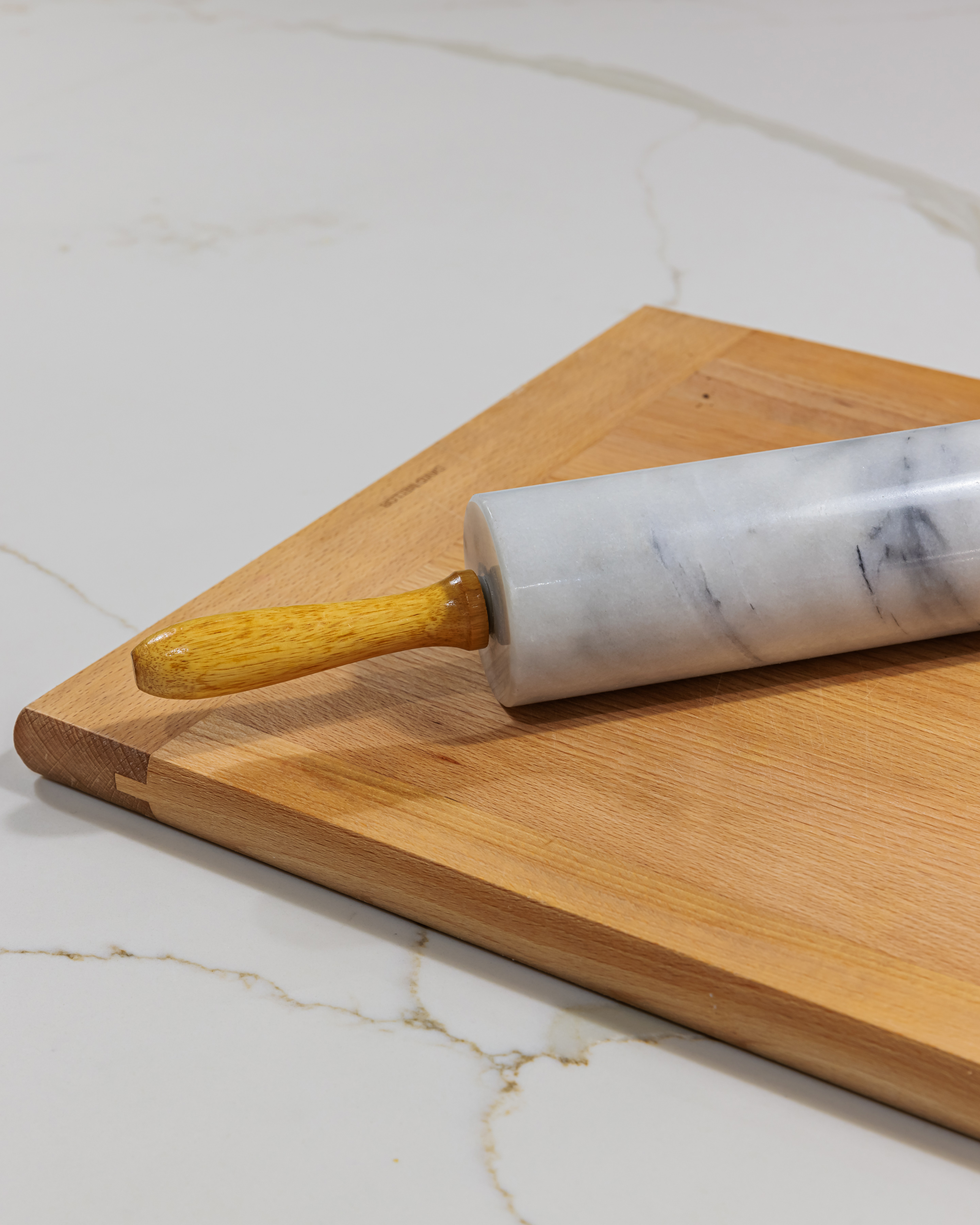 Marble rolling pin with a wooden handle resting on a wooden chopping board, ideal for baking and pastry preparation.