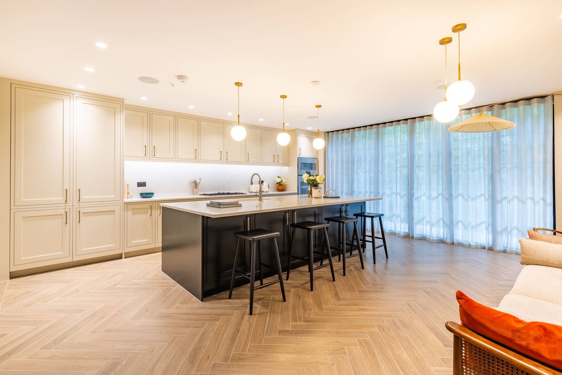 Modern kitchen featuring a central island with bar stools, stylish cabinetry, and large windows allowing natural light. An Arch KBB team member is present, showcasing the contemporary design and functionality of the space.