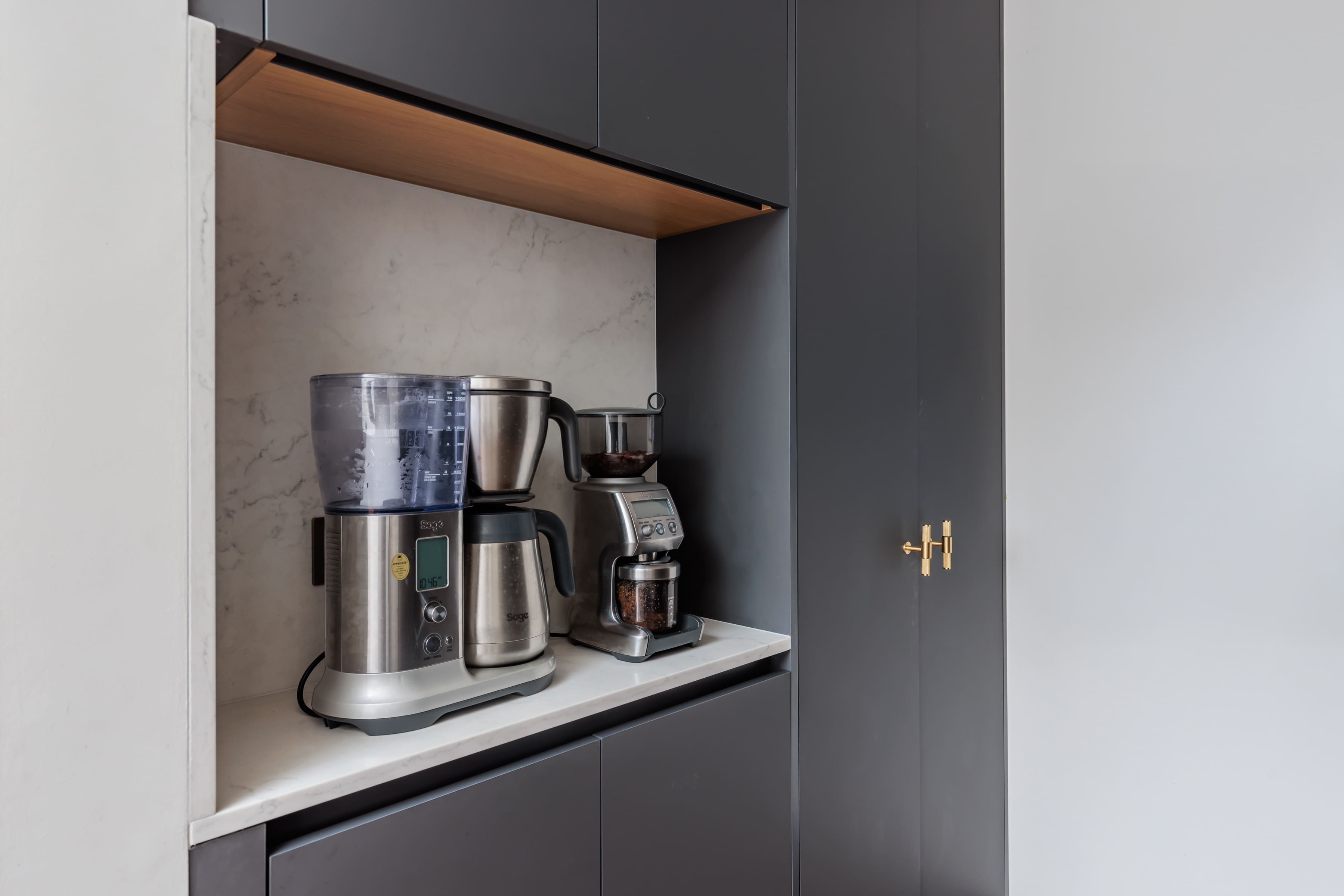 Modern kitchen coffee station featuring a coffee maker, grinder, and brewing equipment set against a sleek marble backdrop and dark cabinetry. Ideal for home barista enthusiasts.