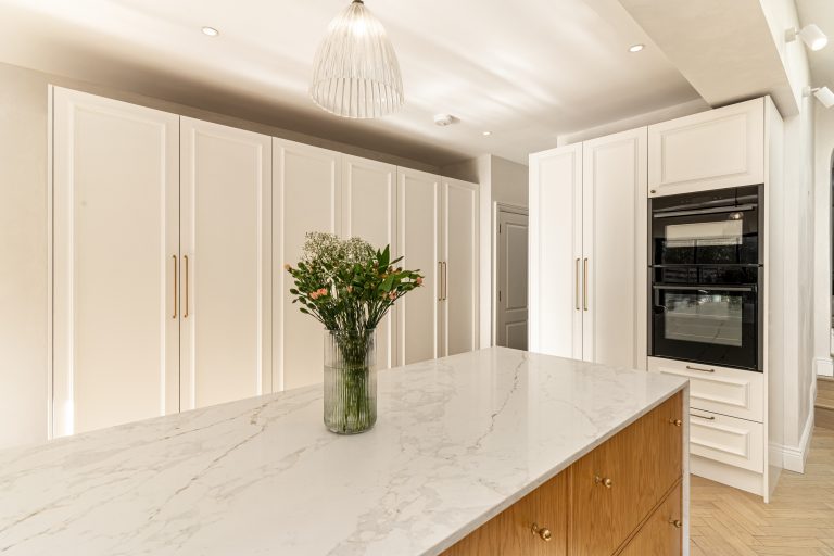 Modern kitchen design in Chiswick featuring marble worktop, elegant cabinetry, integrated oven, and decorative lighting.